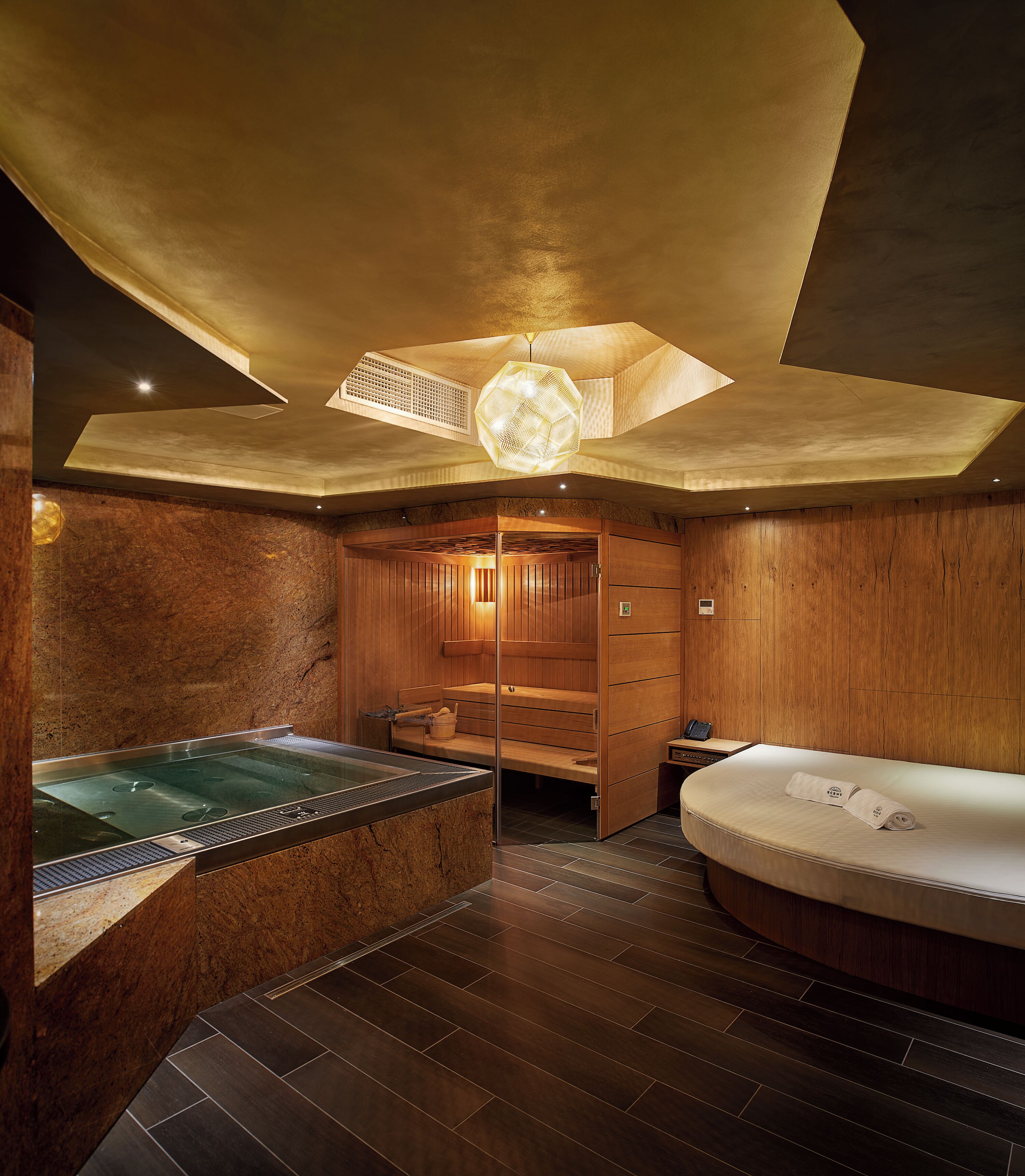 A modern spa room with a hot tub, a massage table, and wooden paneling.