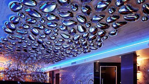 A modern spa area with a marble pool, metal railings, and a ceiling adorned with reflective, metallic elements. - Theatre Hotel (Olomouc)