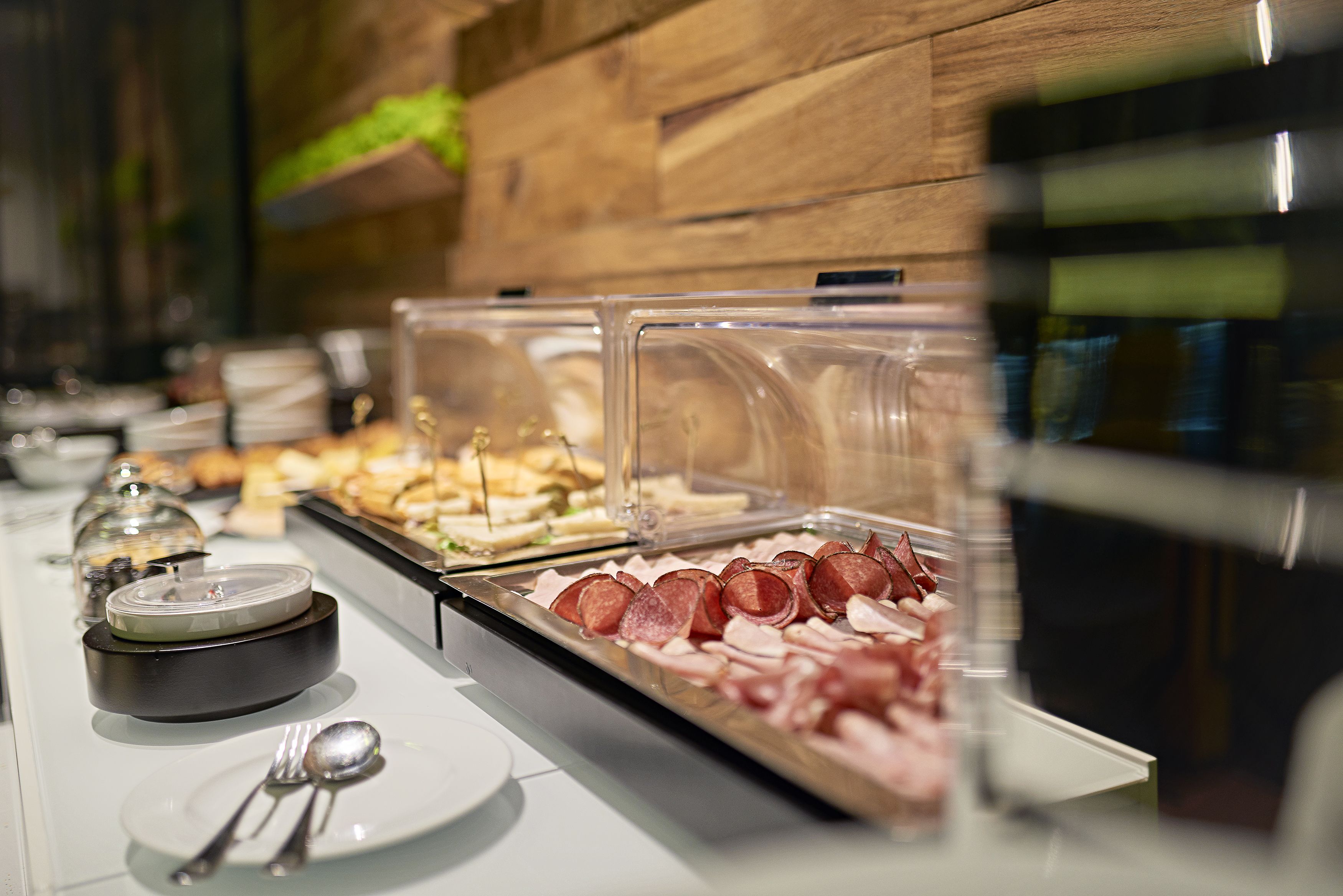 A buffet with various food items, including sliced meats and cheeses, arranged in clear containers.