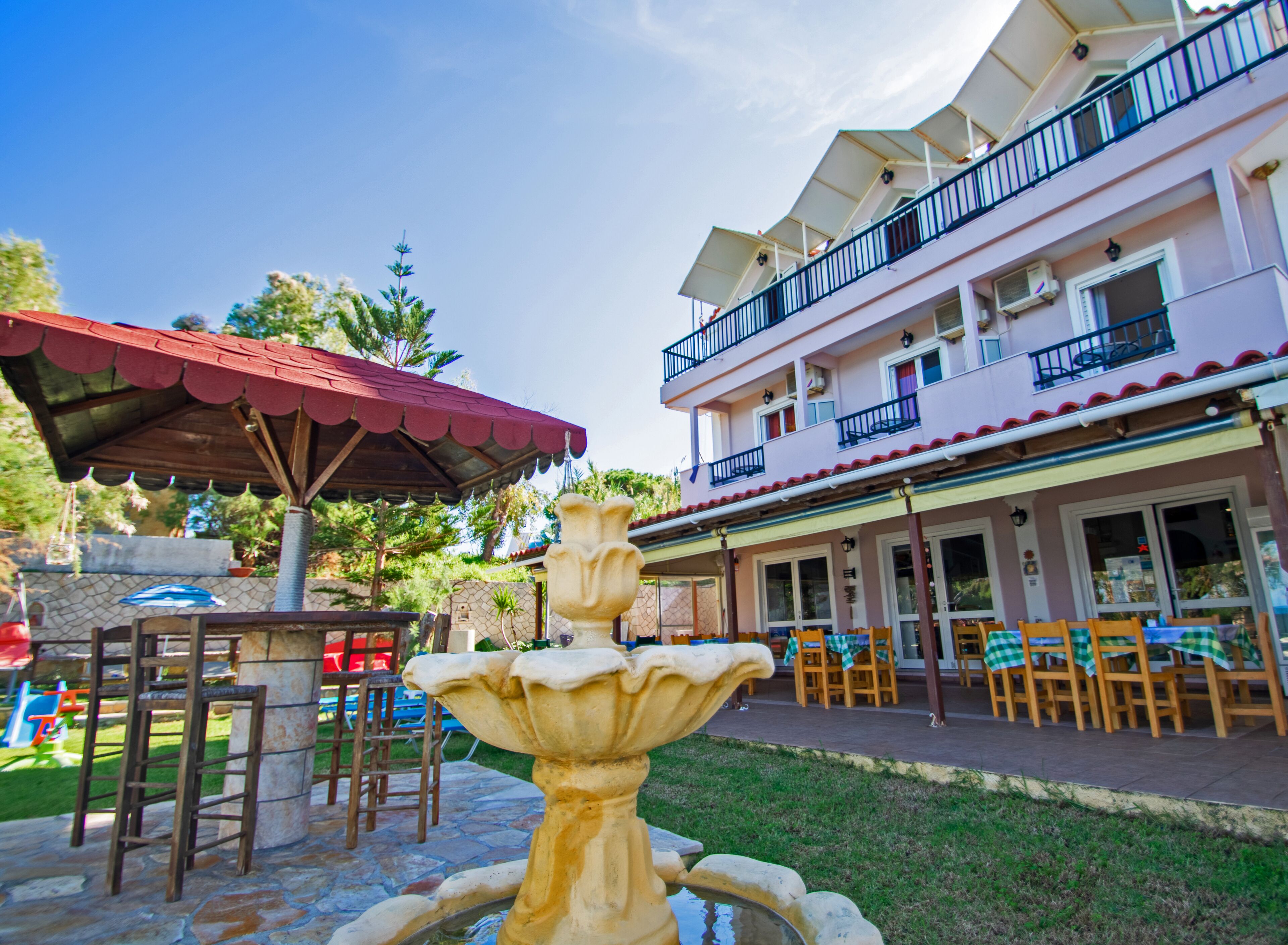 A building with a balcony, outdoor seating, and a fountain.