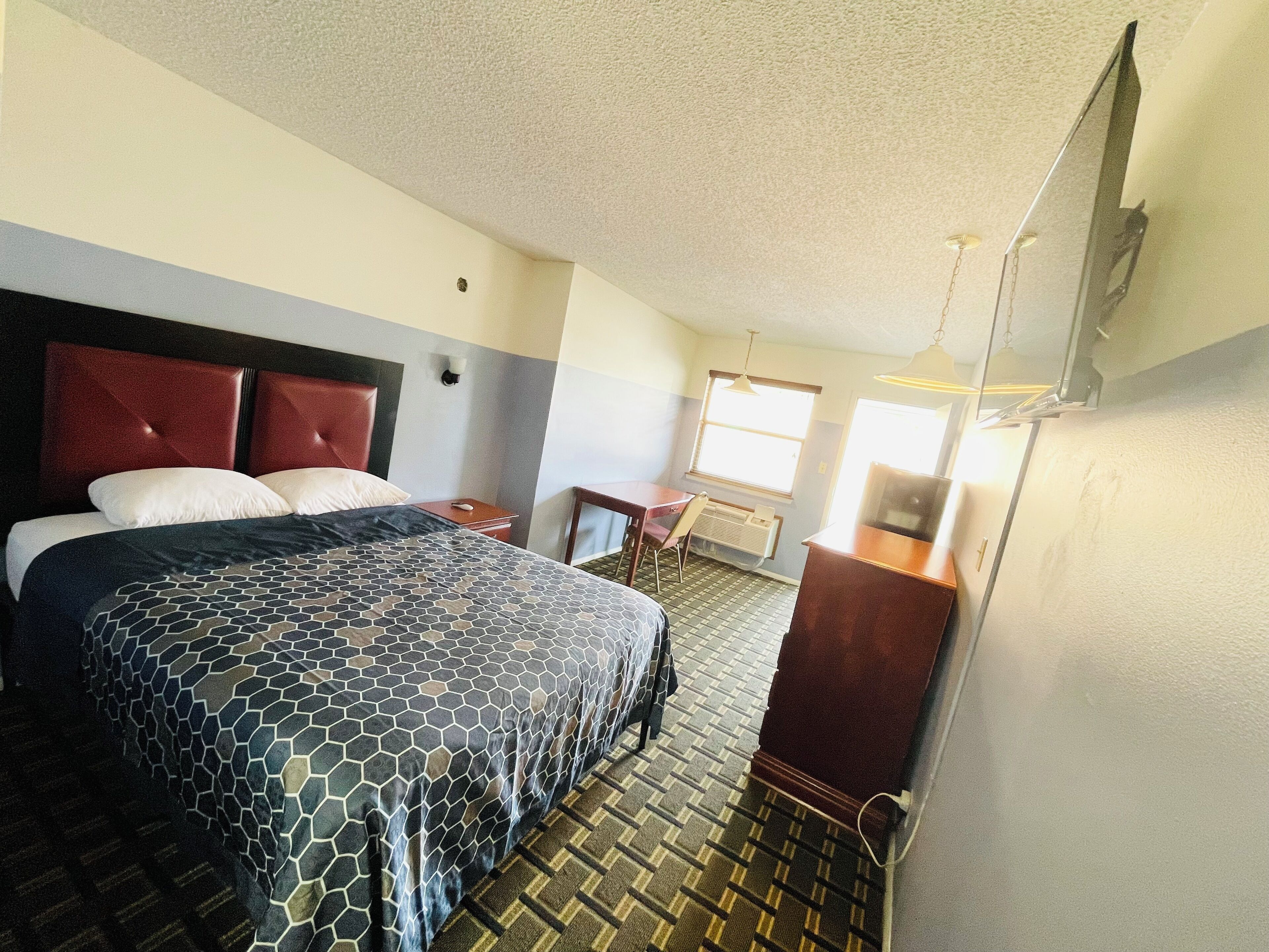 Een hotelkamer met een bed, een bureau, een stoel, een dressoir en een raam.