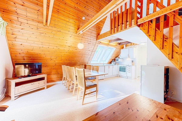 Un interior acogedor de madera con comedor, cocina y televisor.