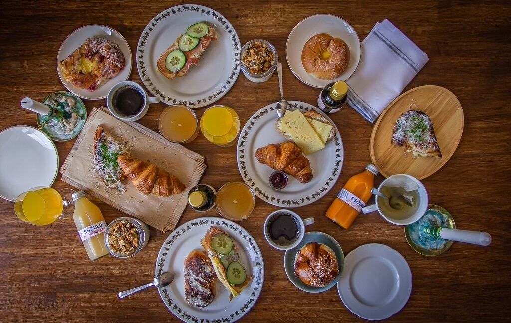 A breakfast table with various dishes, including croissants, cheese, and fruit.