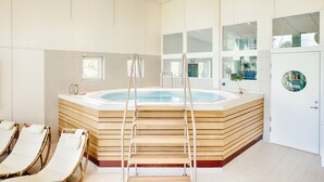 Un espace bien-être comprenant un jacuzzi, des marches en bois et des chaises longues.