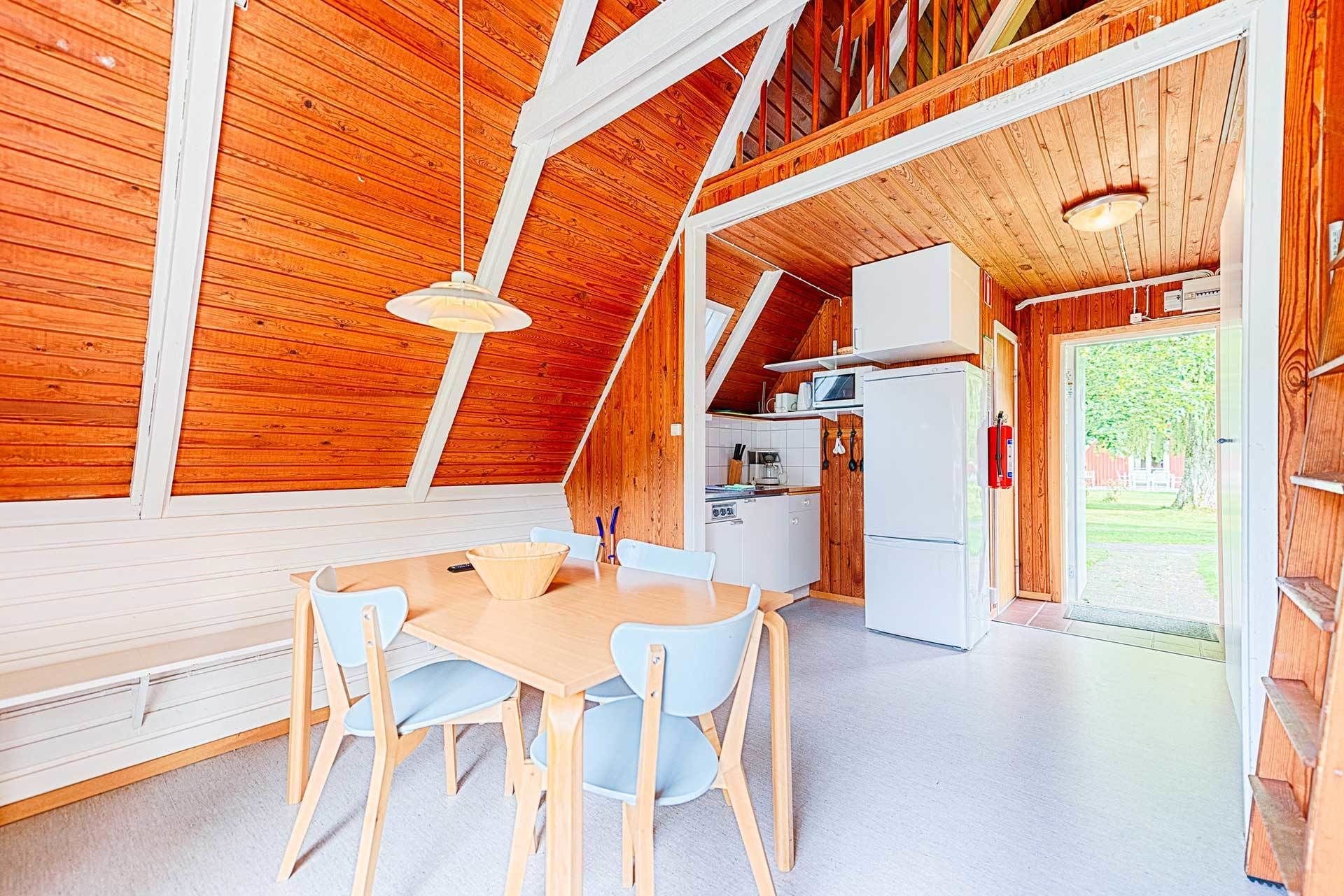 A cozy wooden interior with a dining area, kitchen, and a view of the outdoors.