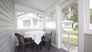 A covered patio with a table and chairs, a view of neighboring houses, and a door leading outside. - Drakes Island Resort (Wells)