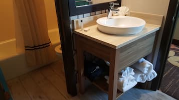 Une salle de bain avec un meuble-lavabo en bois, un lavabo blanc et un porte-serviettes.