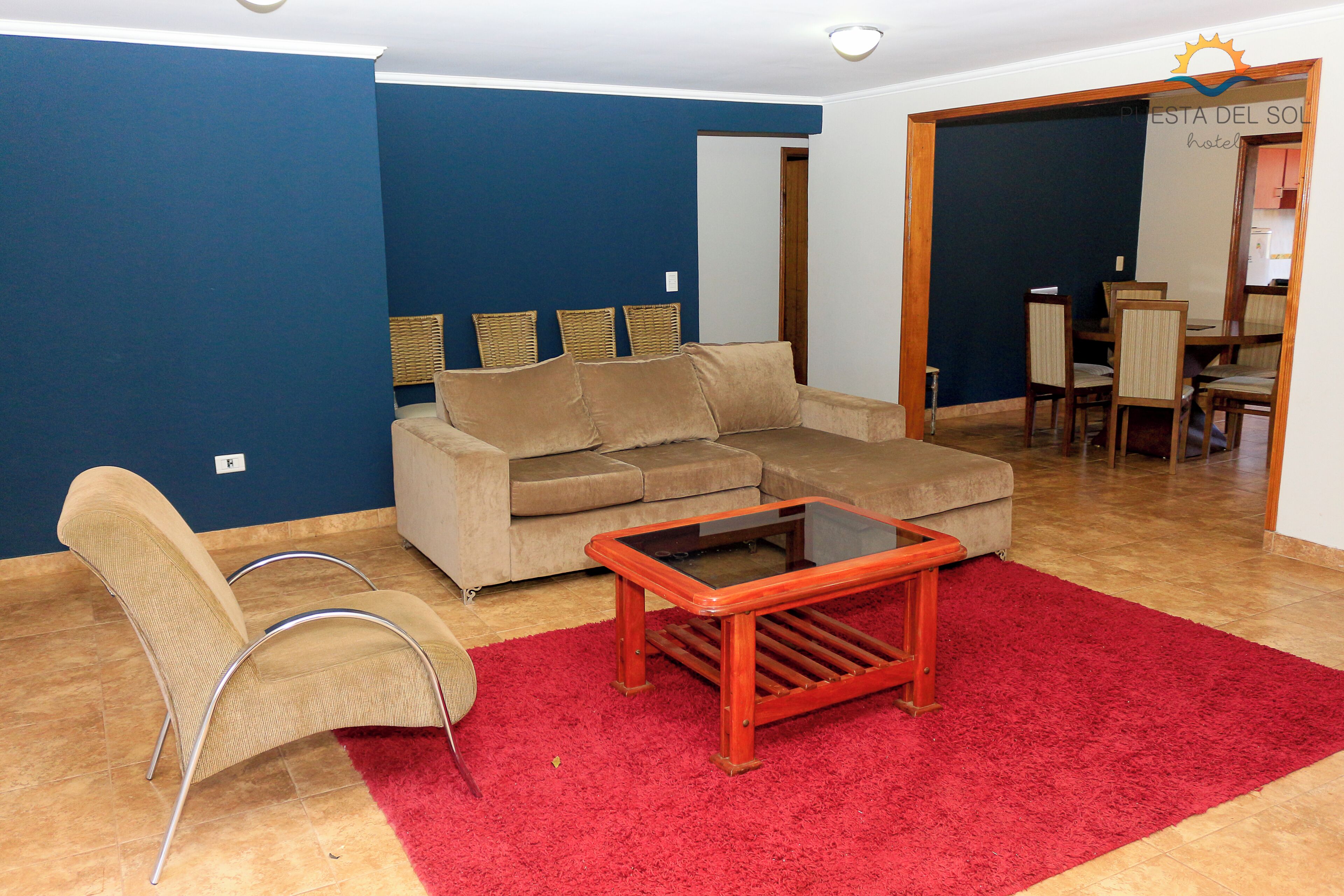 A living room with a sofa, a chair, a coffee table, and a red rug.