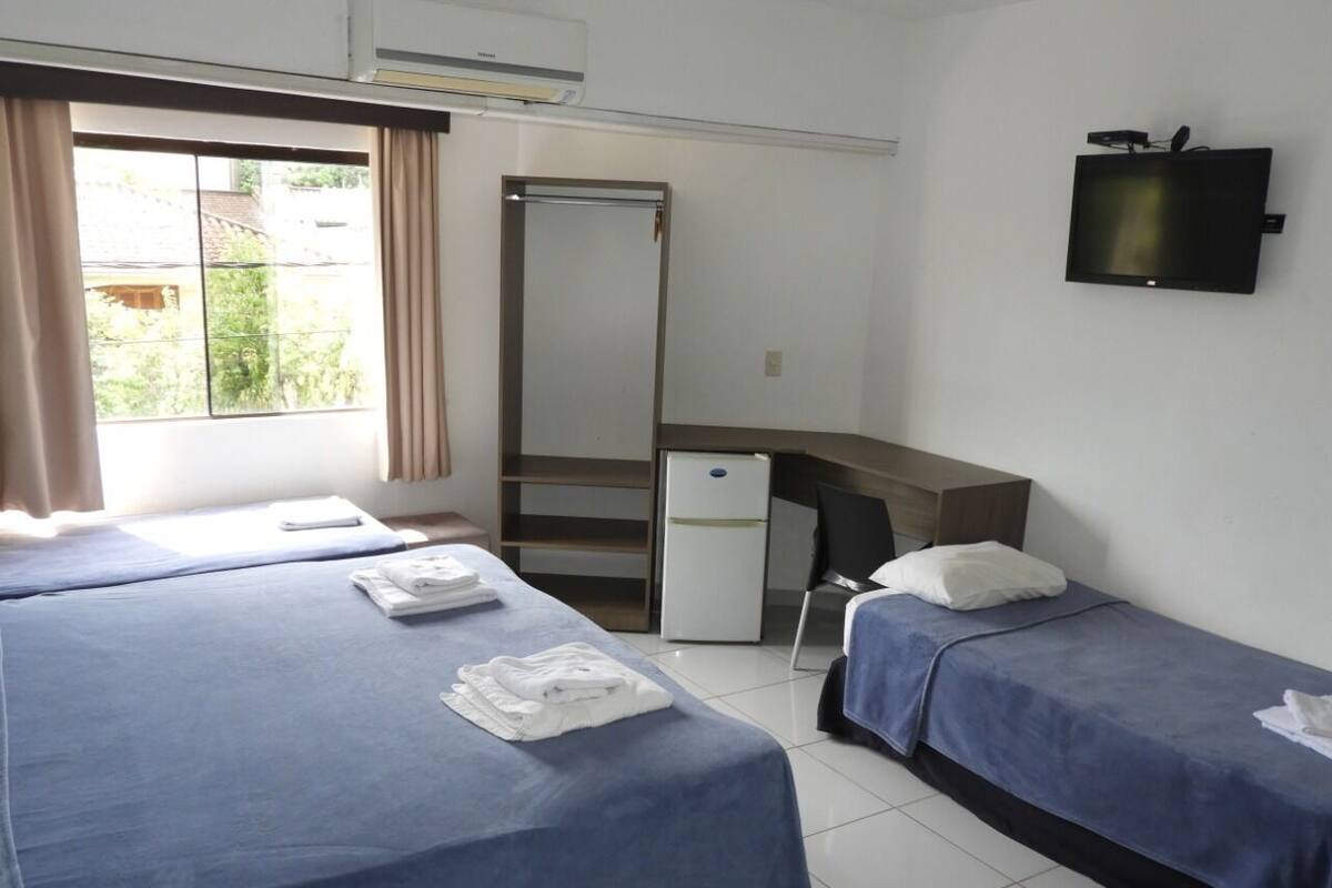 A hotel room with two beds, a desk, a TV, and a wardrobe.