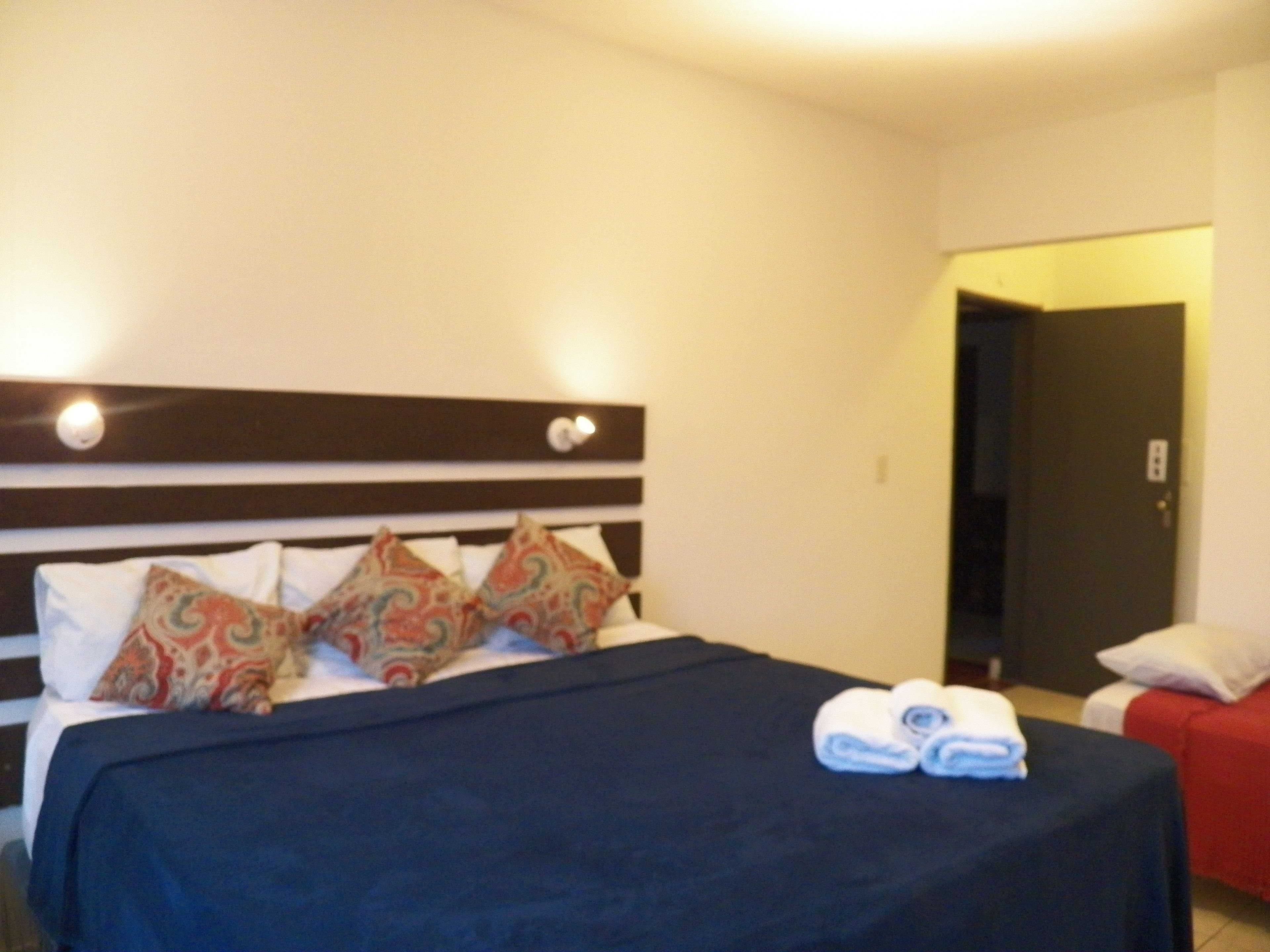 Una habitación de hotel con una cama, almohadas y una toalla doblada sobre la cama.