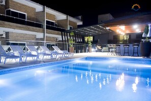 A swimming pool with lounge chairs and a bar area. - Hotel Puesta del Sol (Encarnacion)