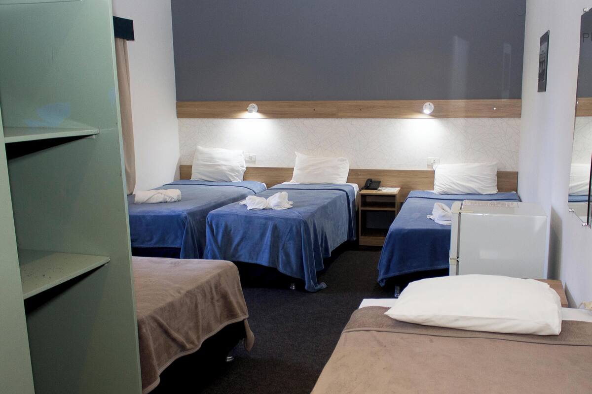 A hotel room with three beds, a desk, and a wardrobe.