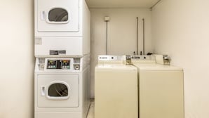 A laundry area with stacked washers and dryers, a utility pole, and a wall-mounted electrical outlet. - Value Inn Kenosha I-94 - Exit 344 (Kenosha)