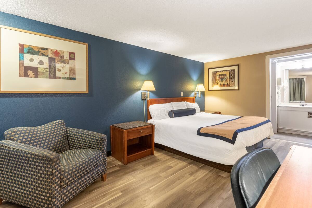 Ein Hotelzimmer mit einem Bett, einer Couch, einem Schreibtisch und zwei Lampen.