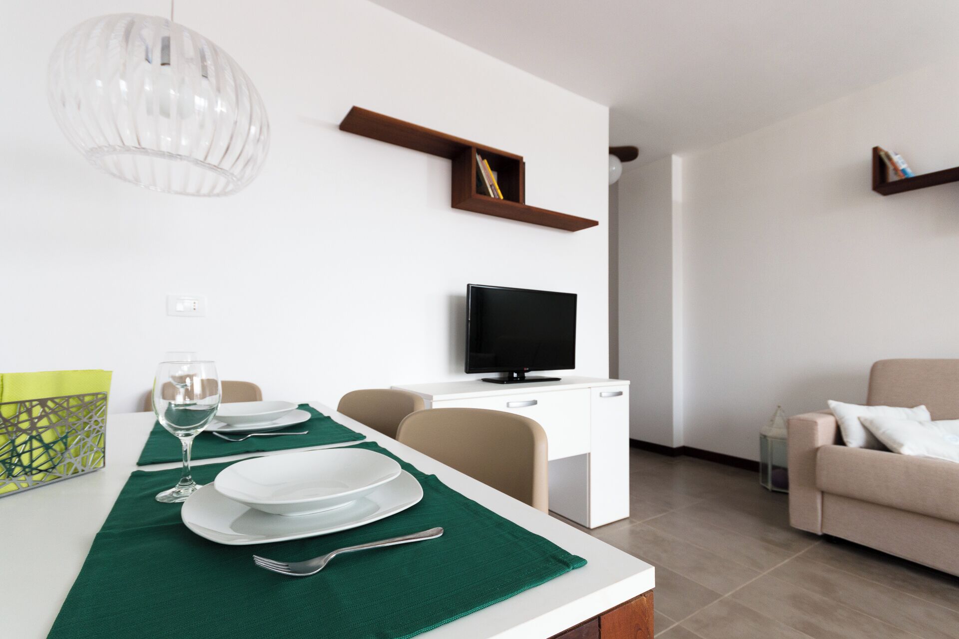 A modern living room with a dining area, a flat-screen TV, and a sofa.