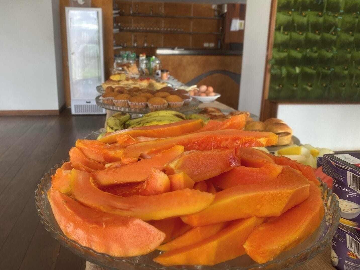 A buffet table with various food items, including sliced fruits and pastries.