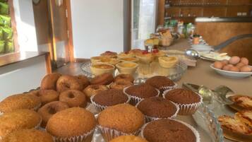 Un tavolo con un buffet di prodotti da forno assortiti, tra cui muffin e crostate.
