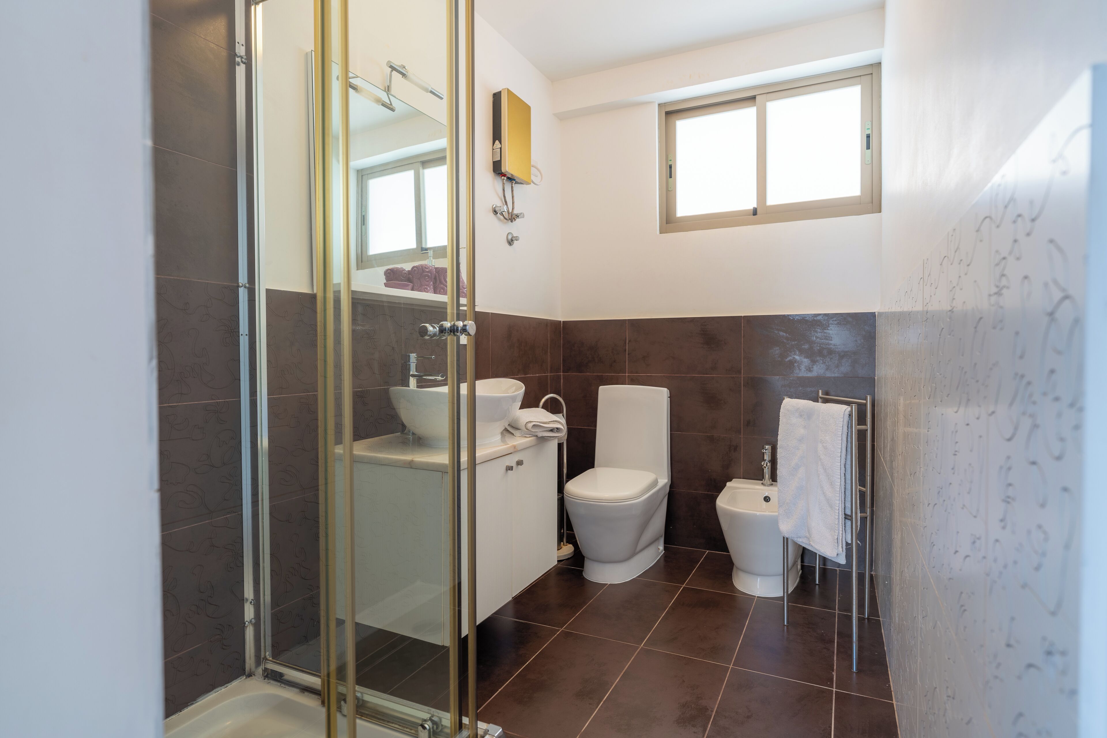 Een moderne badkamer met een douchecabine van glas, een wit wastafelmeubel, een toilet en een bidet.