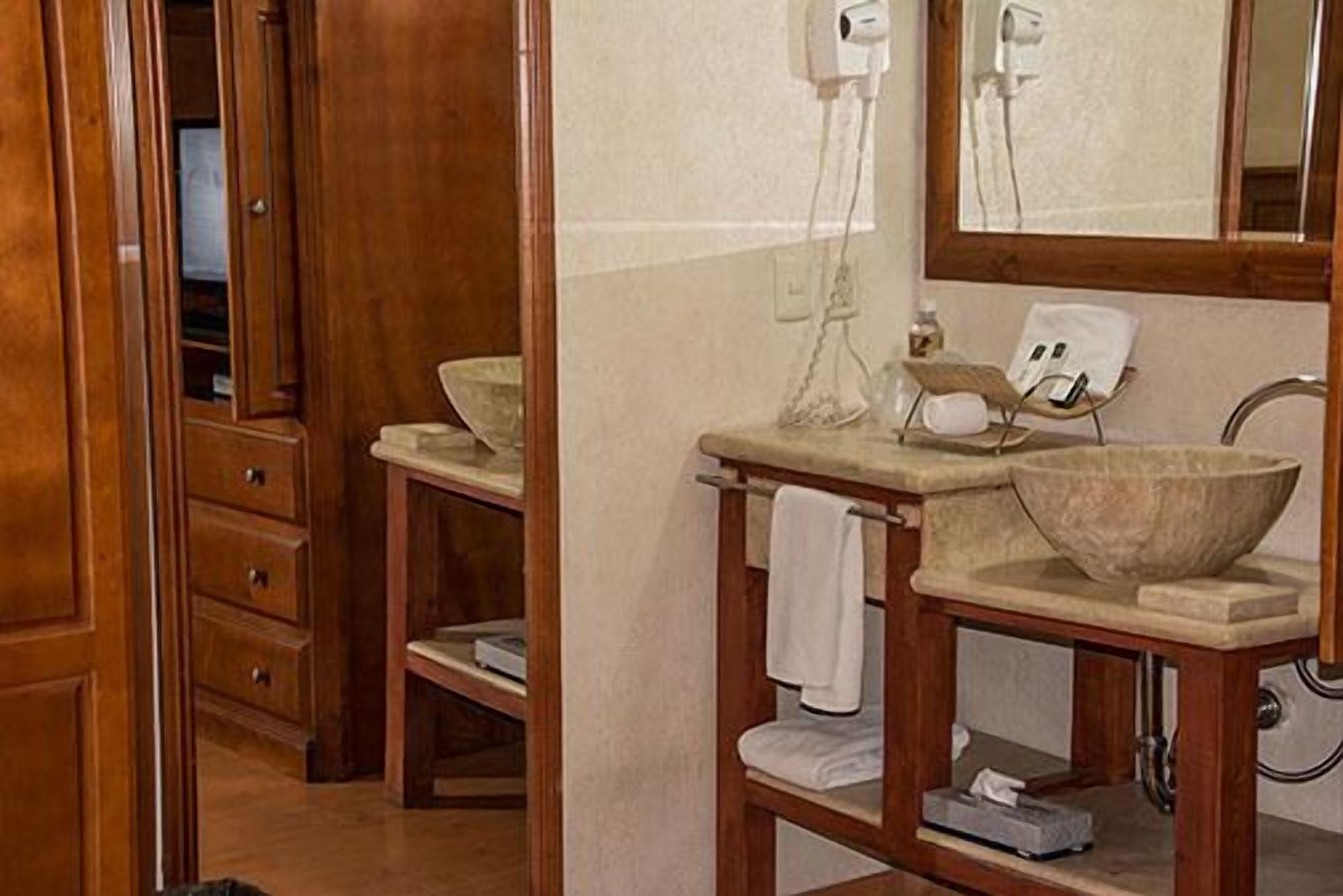 A bathroom with a wooden vanity, a large mirror, and a stone basin.