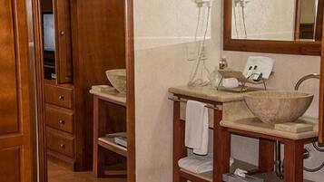 A bathroom with a wooden vanity, a large mirror, and a stone basin.