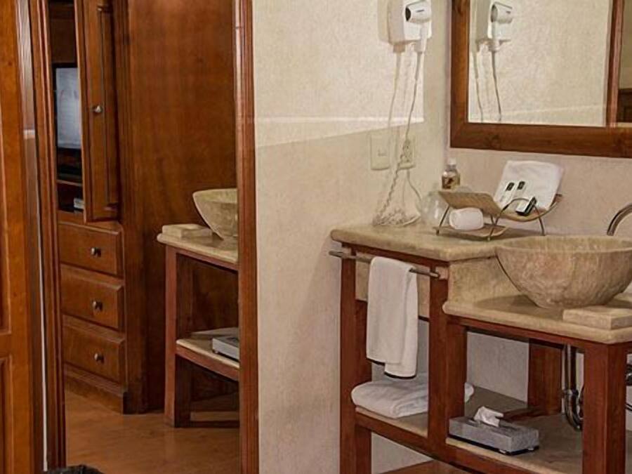 A bathroom with a wooden vanity, a large mirror, and a stone basin.