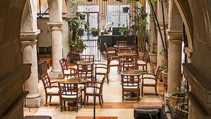 An indoor courtyard with stone arches, wooden furniture, and potted plants. - Hostal De La Monja (Durango)