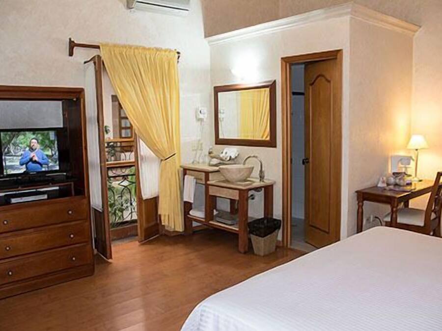 A hotel room with a bed, a TV, a bathroom with a mirror, and a desk with a chair.