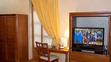 A hotel room with a wooden desk, a television, and a wardrobe.