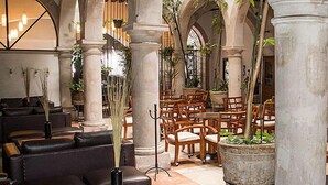 A spacious lobby with high ceilings, large stone columns, and a variety of seating arrangements including sofas and tables. - Hostal De La Monja (Durango)