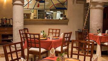 A restaurant with tables set for dining, featuring a stained glass window with fruit design.