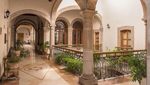 A spacious corridor with arches, columns, and potted plants. - Hostal De La Monja (Durango)