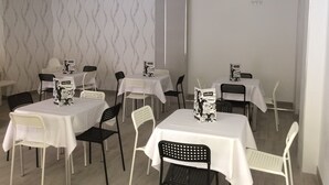 Ein Essbereich mit Tischen und Stühlen, manche mit Tischdecken, andere ohne.