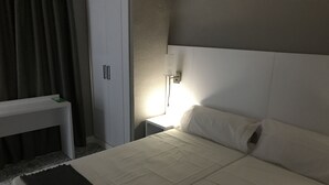 Ein Hotelzimmer mit einem Bett, einem Nachttisch, einer Lampe und einem Kleiderschrank.