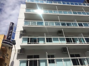 Een hotel met meerdere verdiepingen, balkons, airconditioners en een bord met de tekst 'Banidorm Blue Beach'.