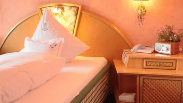 Quarto de hotel com cama, mesa de cabeceira com rádio e telefone, e luminária na parede.