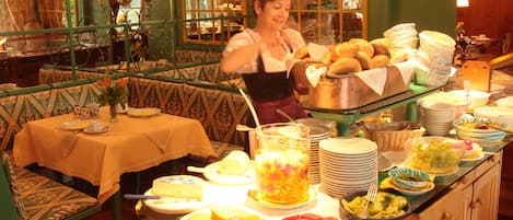 Ein reichhaltiges Buffet mit verschiedenen Speisen und einer Person, die bedient.