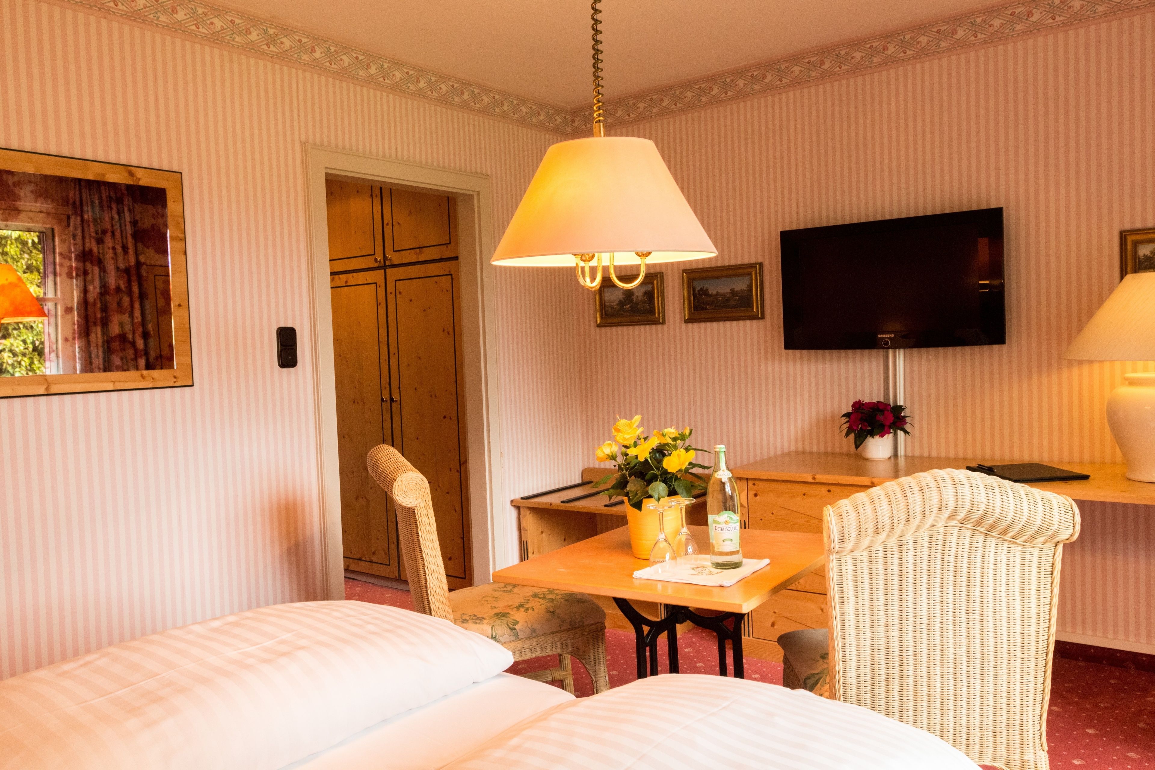 Et hotelværelse med en seng, et skrivebord med lampe, et fjernsyn og en stol.