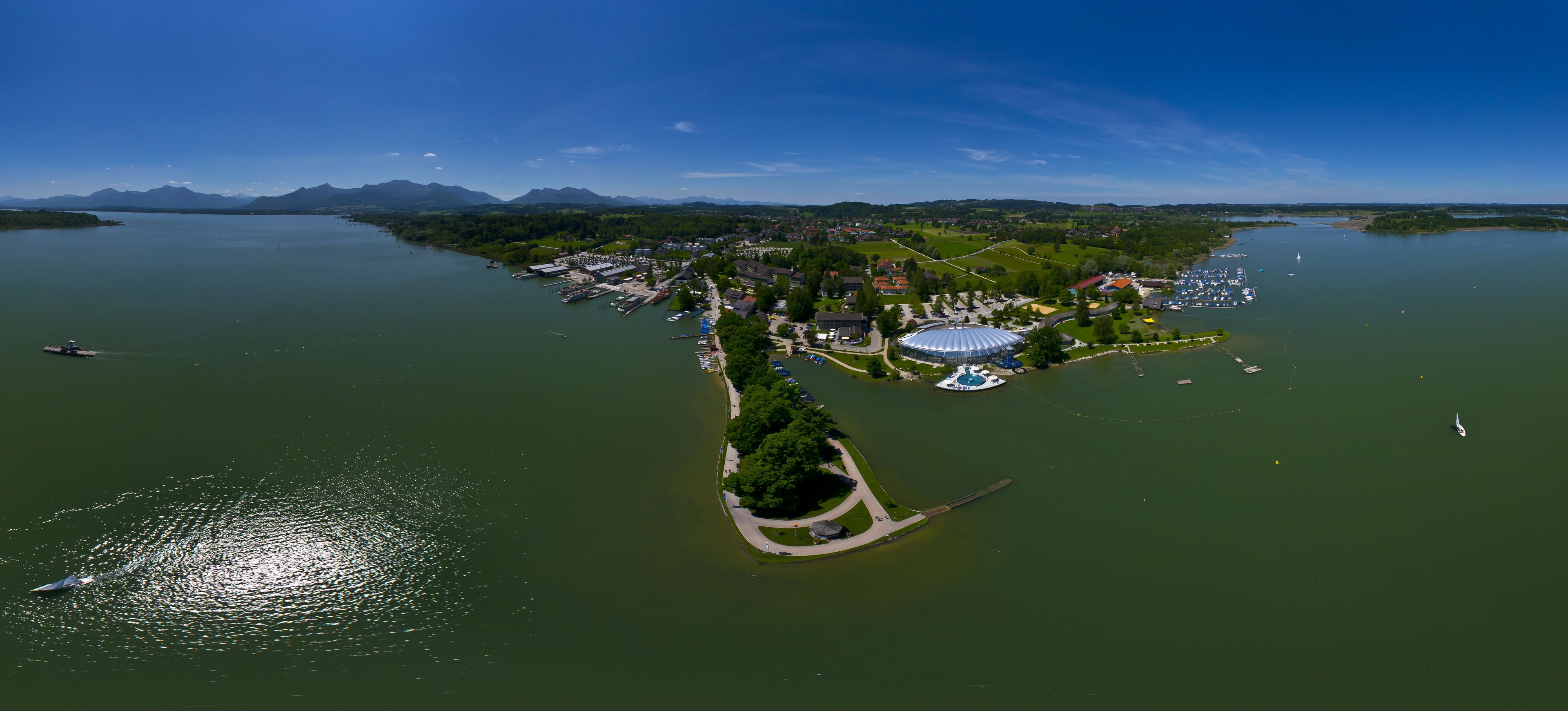 Vue aérienne d’une ville située au bord d’un lac, avec un port de plaisance, un grand stade et des quartiers résidentiels.