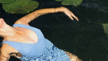A person floating in water with lily pads.