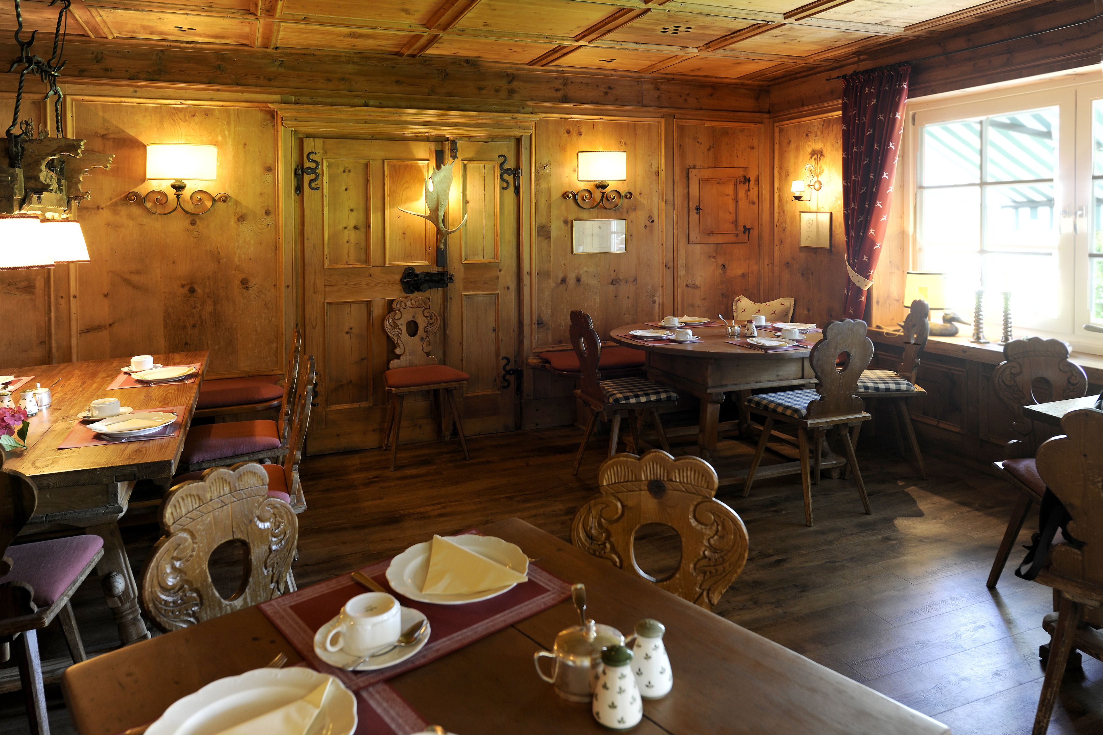 A wooden interior with a dining area, wooden walls, and two wall-mounted lamps.