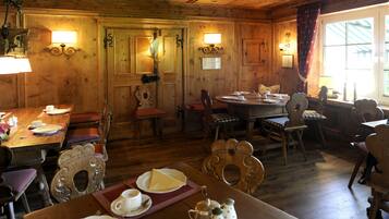 A wooden interior with a dining area, wooden walls, and two wall-mounted lamps.