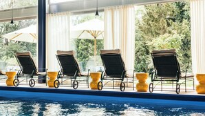 A swimming pool with lounge chairs and umbrellas. - Garden Hotel Reinhart (Prien am Chiemsee)