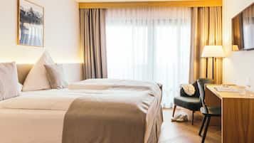 Comfortable accommodations feature a large bed, desk, and chair, with a window and curtains.