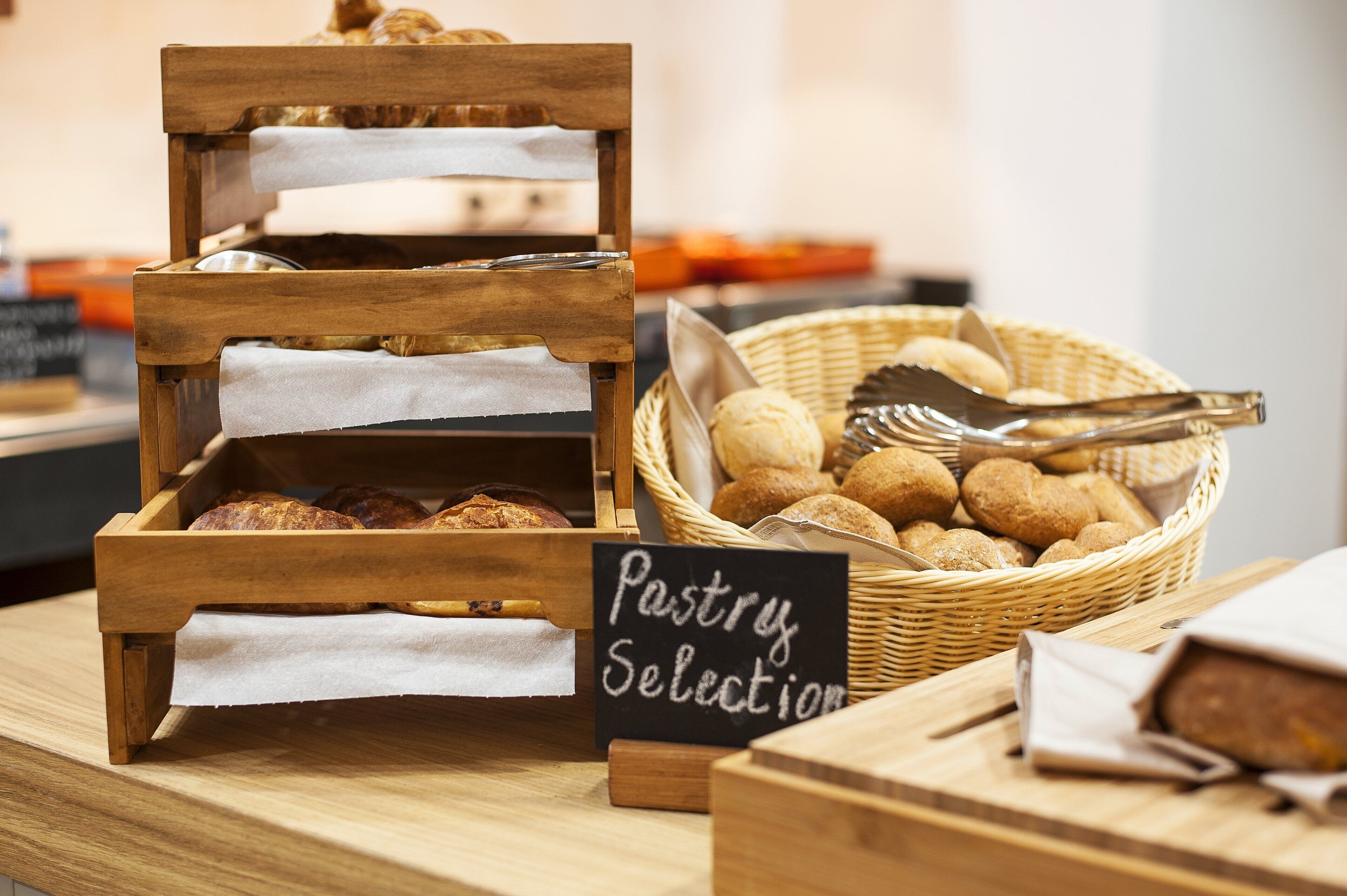 A bakery display with bread and pastries, a sign reading "Pastry Selection," and a basket of croissants.