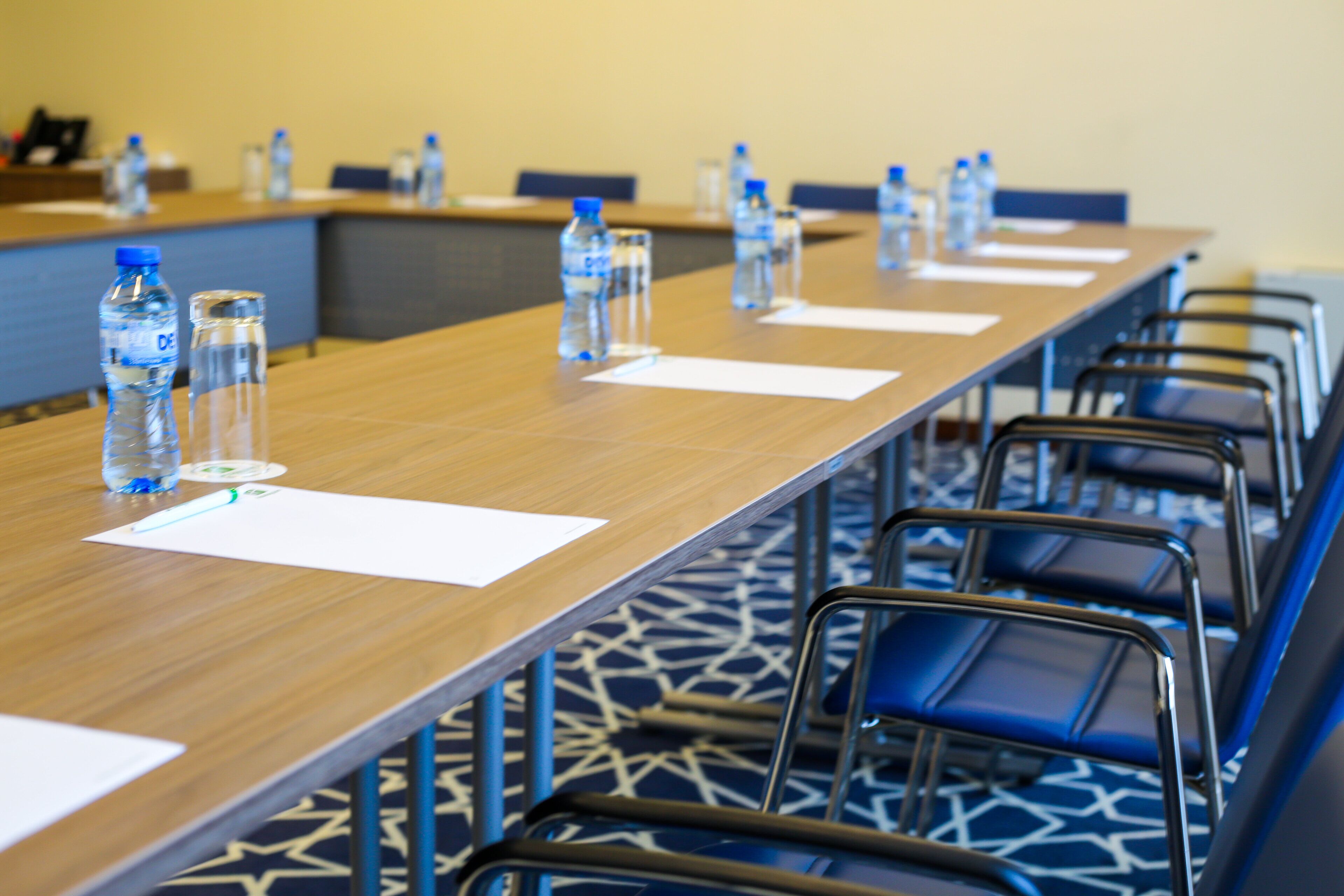 A conference room with a long table, chairs, water bottles, and papers.