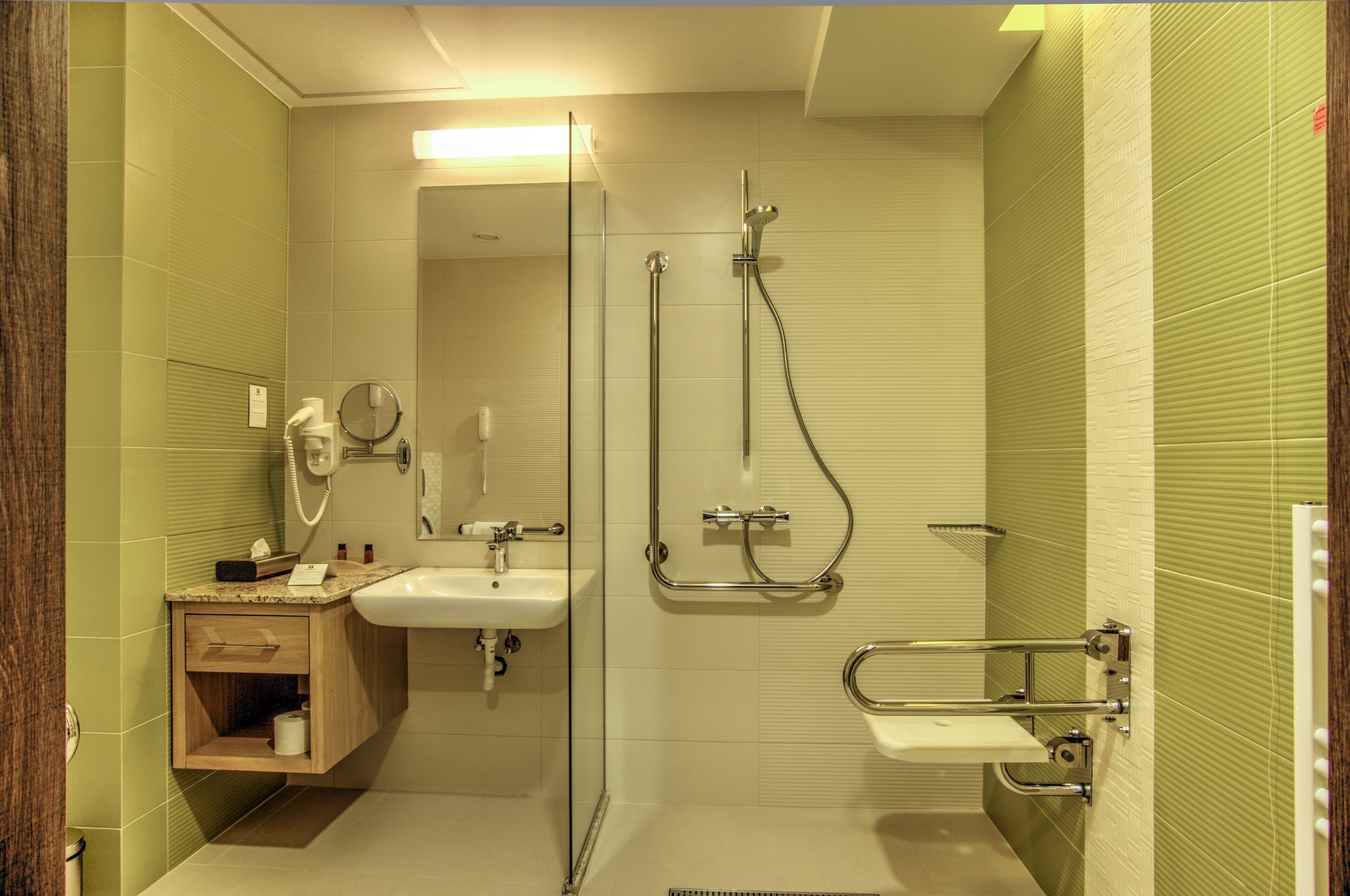 Un baño con cabina de ducha de vidrio, un lavamanos y un mueble de tocador con espejo.