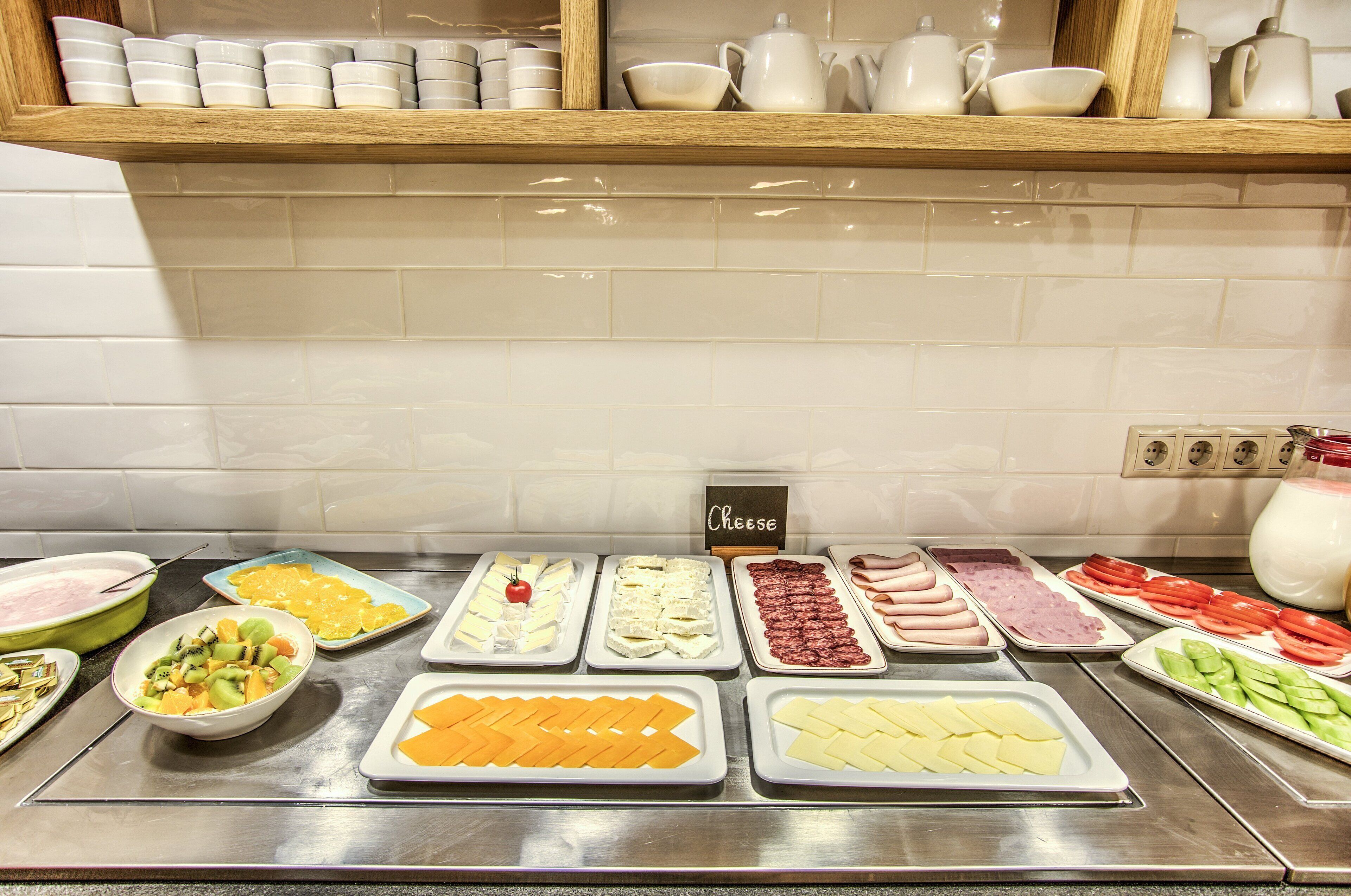 Buffet com diversas opções de comida, incluindo frutas, queijos e carnes.