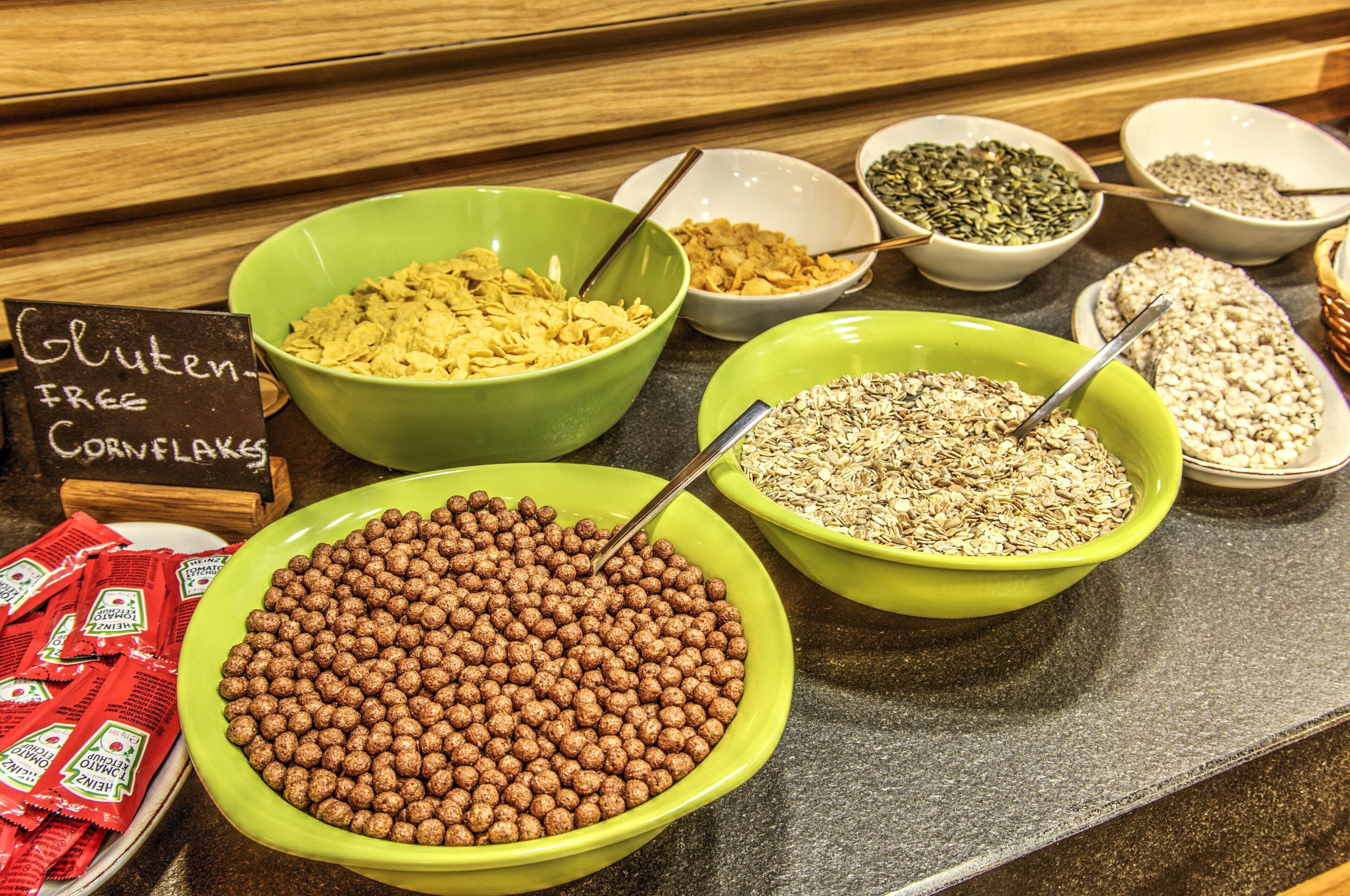 Diversas opciones de cereales sin gluten y con hojuelas de maíz expuestas en tazones sobre una encimera.