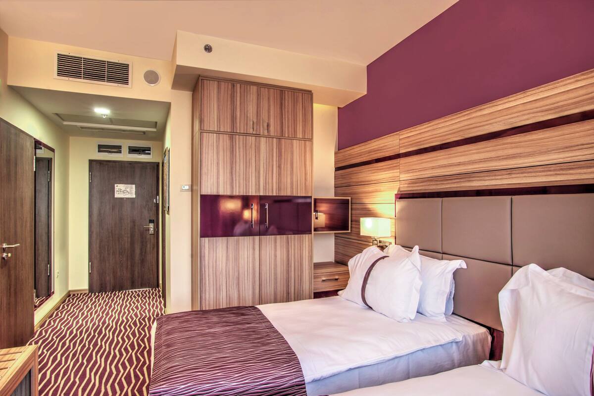 A hotel room with a bed, a wardrobe, a television, and a bedside table.