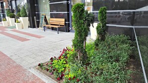 A landscaped area with a bench and a signboard, surrounded by neatly trimmed bushes and flowering plants. - Holiday Inn Plovdiv by IHG (Plovdiv)